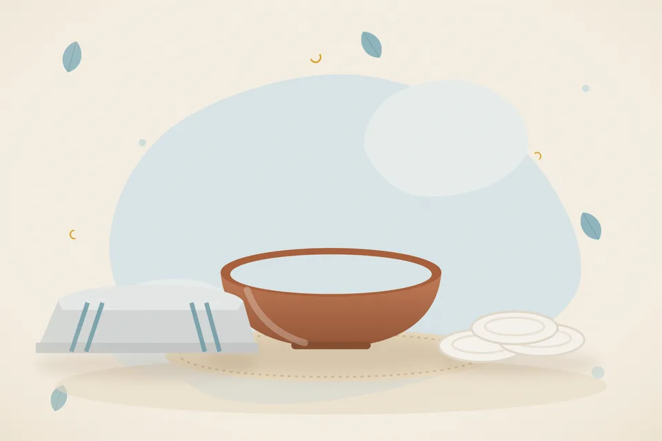 A small brass bowl of ghee and a cotton cloth on a wooden board