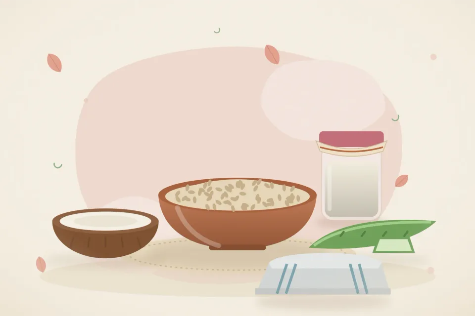 A bowl of oats, half a coconut with a jar of coconut oil, aloe vera leaf and a soft cotton cloth on a rose-pink background