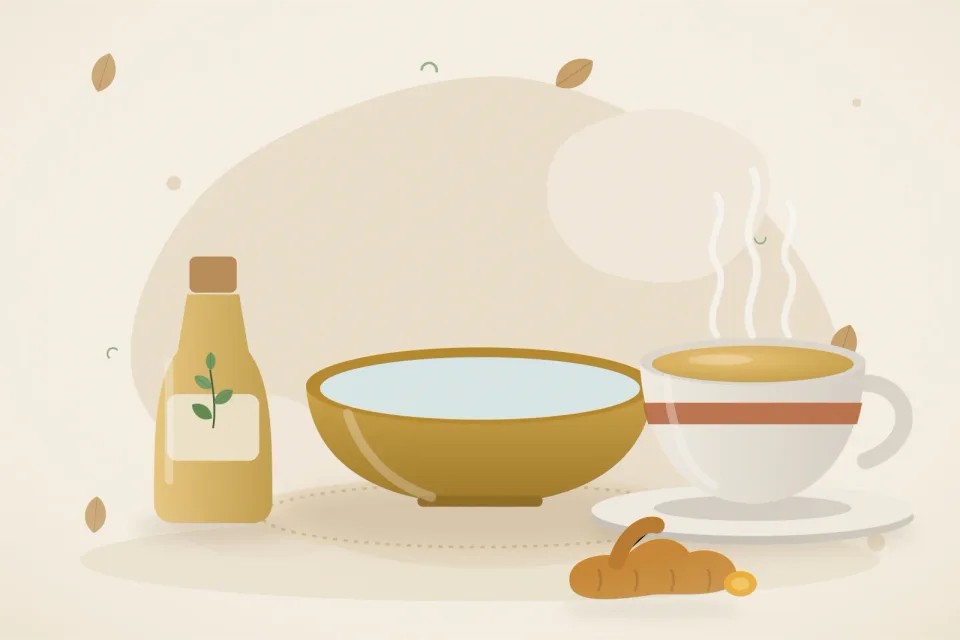 A brass bowl of warm water, a bottle of sesame oil, a cup of turmeric-ginger tea and fresh turmeric root on a sandy beige background