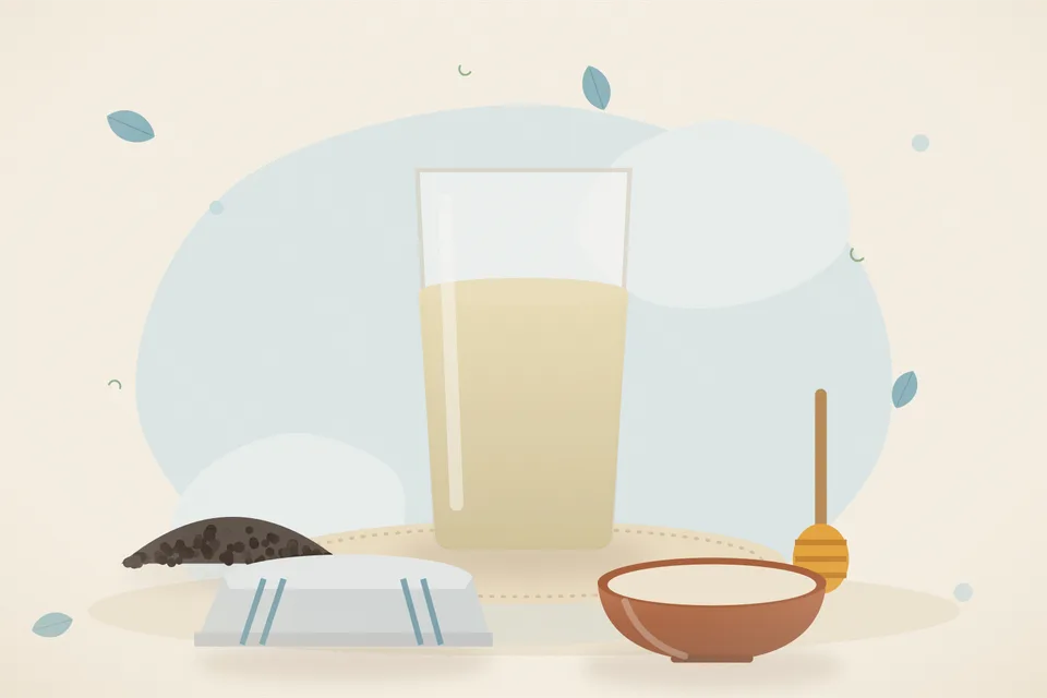 A cup of warm water, a few black peppercorns and a spoon of honey on a small plate on a kitchen table.