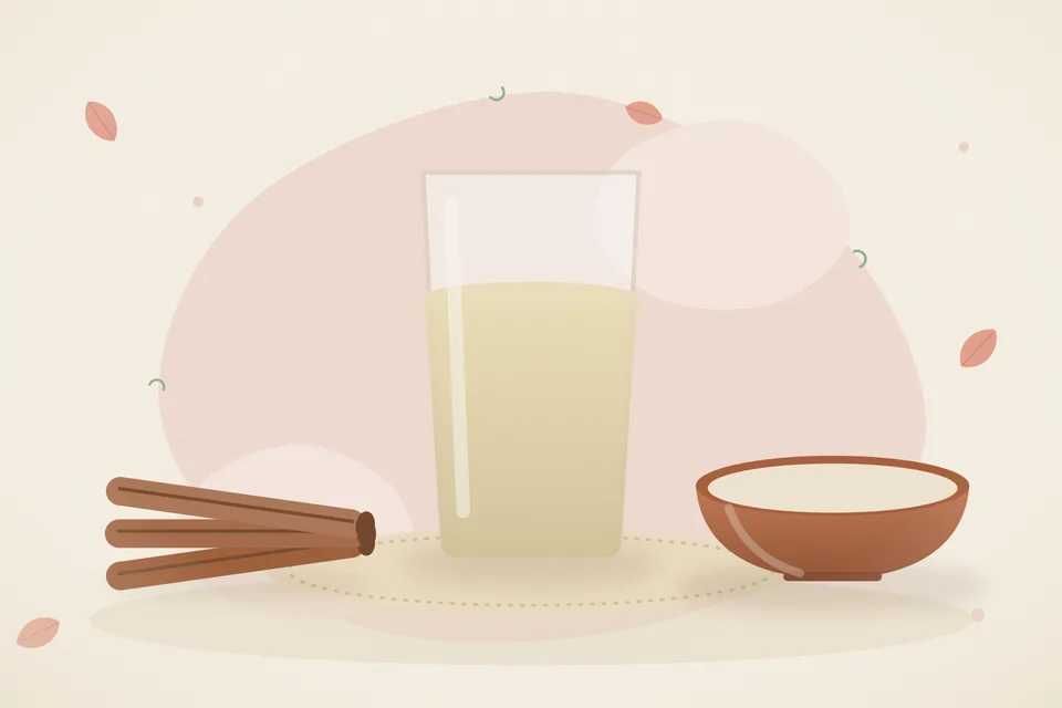 A bowl of plain oat porridge with a pinch of cinnamon on top, next to a small oats jar and a cinnamon stick on a wooden board.