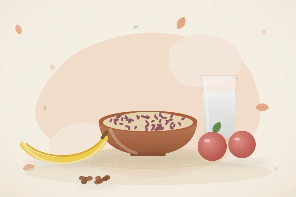 Bowl of soaked raisins, a banana, red apples and a glass of water on a peach background